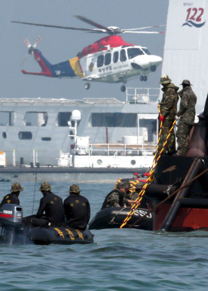 합동구조팀원들이 24일 오전 전남 진도군 병풍도 세월호 침몰 해상을 수색하는 민간잠수사들(머구리)을 위해 공기공급호스를 잡아주고 있다.  연합뉴스