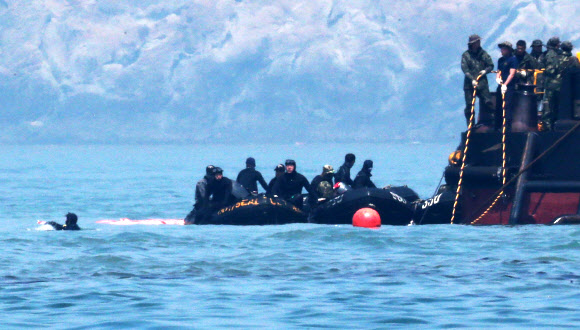 합동구조팀 잠수사(왼쪽)이 24일 오전 전남 진도군 병풍도 세월호 침몰 해상을 수색하고 있다. 오른쪽 노란줄은 민간잠수사들(머구리)을 위한 공기공급호스. 연합뉴스