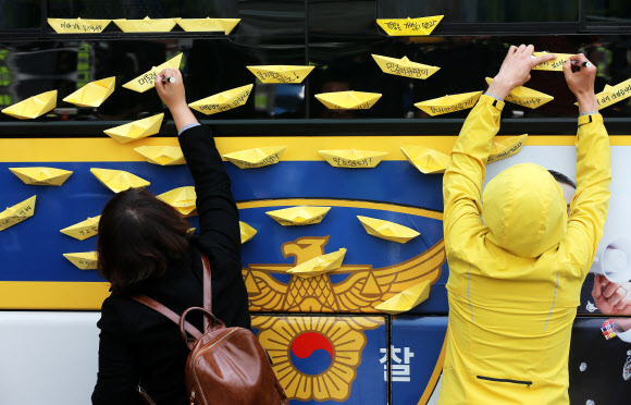 9일 오전 서울 종로구 청운동 주민센터 앞에서 세월호 침몰 사고 유가족들이 대통령 면담을 요구하고 있는 가운데 한 시민이 청와대 진입을 막는 경찰차에 노란 종이배를 붙이고 있다. 연합뉴스