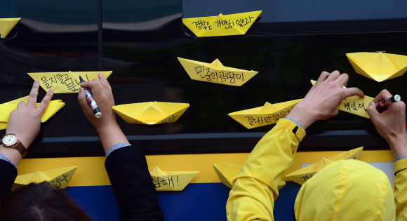 9일 서울 종로구 청운동사무소 앞에서 세월호 침몰사고 희생자 유가족들이 대통령과의 대화를 요구하고 있는 가운데 시민들이 노란종이배를 경찰버스에 붙이고 있다.  정연호 기자 tpgod@seoul.co.kr