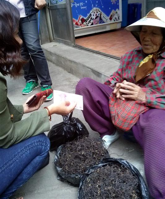 제주 오일장 할망 장터에서 한 할머니가 손수 채취해 말린 고사리를 중국인 관광객에게 팔고 있다.