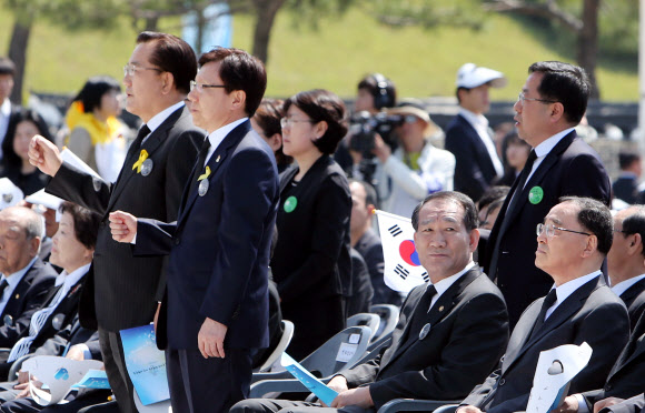 국가보훈처가 5·18기념식에서 ‘님을 위한 행진곡’ 제창을 거부해 유족과 5월 단체들이 기념식에 불참한 가운데 18일 오전 광주 북구 운정동 국립 5·18민주묘지에서 열린 5·18기념식에서 박준영 전남지사 등 일부 인사들이 일어서서 ‘님을 위한 행진곡’을 부르자 박승춘 보훈처장이 다른 곳을 보고 있다. 연합뉴스