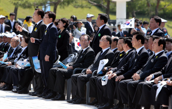 국가보훈처가 5·18기념식에서 ‘님을 위한 행진곡’ 제창을 거부해 유족과 5월 단체들이 기념식에 불참한 가운데 18일 오전 광주 북구 운정동 국립 5·18민주묘지에서 열린 5·18기념식에서 박준영 전남지사(맨 오른쪽) 등 일부 인사들이 일어서서 ‘님을 위한 행진곡’을 부르자 박승춘 보훈처장이 다른 곳을 보고 있다. 연합뉴스 