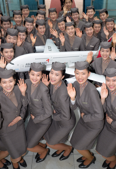 아시아나항공 본사에서 신입 승무원들이 에어버스 A-380기의 모형과 함께 손을 흔들고 있다.  