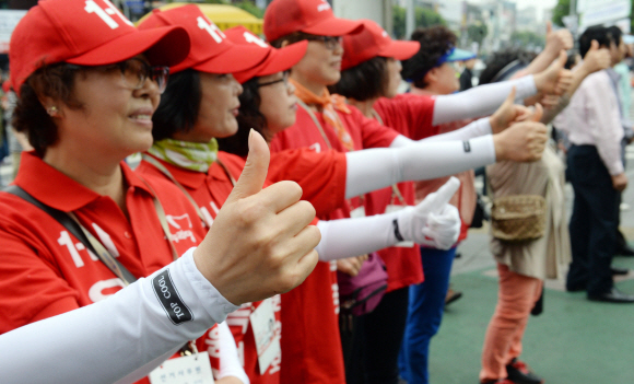 새누리당 선거운동원들이 25일 서울 광진구 건대입구역 주변에서 기호 1번을 의미하는 엄지손가락을 추켜세우며 지지를 호소하고 있다. 정연호 기자 tpgod@seoul.co.kr