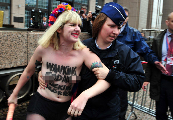 4일(현지시간) 상의탈의를 한 우크라이나 여성인권단체(FEMEN)의 한 여성이 벨기에 브뤼셀 G7 정상회담이 열리는 유럽의회본부 앞에서 시위를 하던 중 경찰에게 끌려가고 있다. ⓒ AFPBBNews=News1