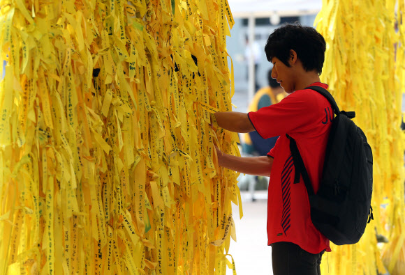 한 시민이 서울광장에 마련된 세월호 희생자 추모 공간에 노란리본을 달고 있다.  연합뉴스