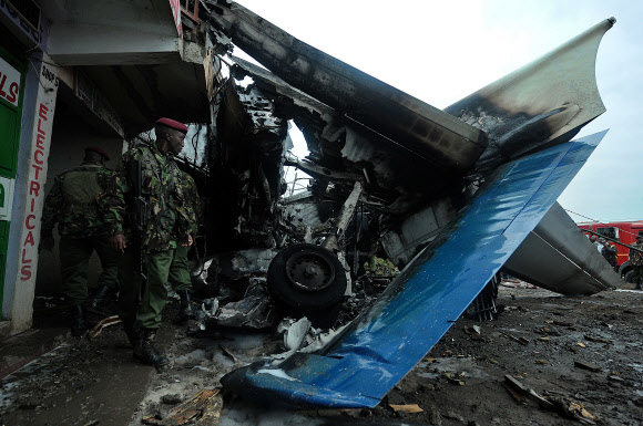 케냐 군인이 2일(현지시간) 케냐 수도 나이로비의 조모 케냐타 국제공항 부근 엠바카시 지역 상업 건물에 충돌해 산산조각 난 화물기 조각들을 바라보고 있다. /ⓒ AFPBBNews=News1