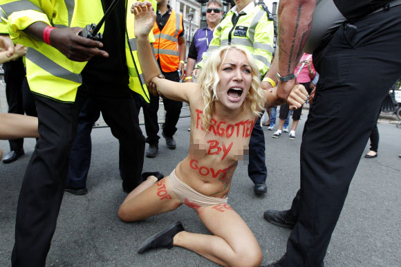 7일(현지시간) 영국 런던 중심부 국회의사당 앞 광장에서 우크라이나 여성 인권단체 피멘(femen) 회원들이 상의를 탈의한 채 여성할례(FGM)를 반대하는 반누드시위를 벌이던 중 경찰에게 끌려가고 있다. ⓒ AFPBBNews=News1