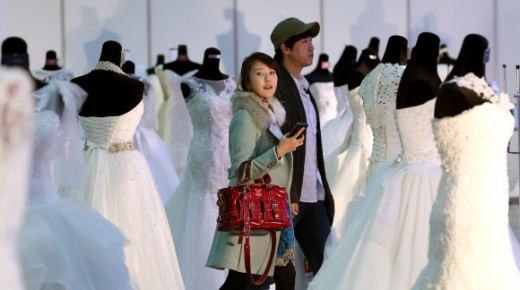 한 예비 부부가 웨딩박람회장에서 드레스를 둘러보고 있다. 연합뉴스