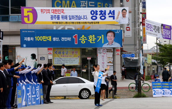 7·30 국회의원 재보궐선거 운동이 시작된 17일 오전 광주 광산구 수완동의 거리에서 광주 광산을 선거구에 출마한 후보들의 선거 현수막이 걸려 있는 가운데 모 후보와 선거운동원들이 거리인사를 하고 있다.  연합뉴스