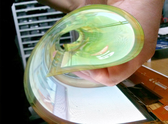 LG디스플레이 직원이 곡률반경 30R을 자랑하는 18인치 플렉시블 OLED를 말아서 시연하고 있는 모습.   LG디스플레이 제공