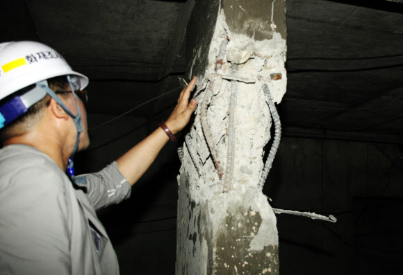 119구조대원이 24일 균열이 생겨 콘크리트와 철근이 노출된 광주시 북구의 한 아파트 지하 기둥을 손으로 만지며 살펴보고 있다.  광주 연합뉴스