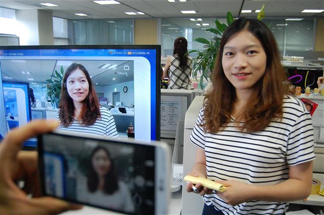 ‘U+LTE생방송’ 개발에 참여한 김성주 대리의 모습을 스마트폰으로 찍어 TV로 생중계하는 모습. 찍고 있는 영상이 TV 화면에 그대로 뜨고 있다. LG유플러스 제공