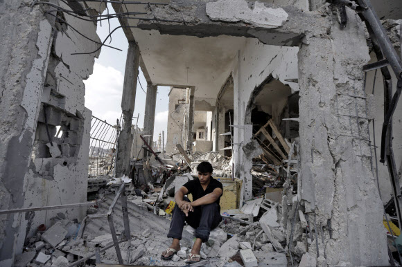 팔레스타인 주민 파디 에아젤라(20)가 5일(현지시간) 이스라엘 공습으로 무너진 자신의 가게에 허망하게 앉아 있다. 그는 가족과 함께 가자지구 베이트라히야에서 슈퍼마켓을 운영해 왔다. 베이트라히야 AP 연합뉴스
