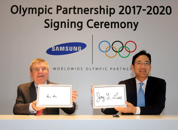 이재용(오른쪽) 삼성전자 부회장이 17일 중국 난징 페어먼트 호텔에서 오는 2020년까지 삼성전자가 올림픽 공식 후원을 연장하는 계약을 체결한 뒤 토마스 바흐 국제올림픽위원회(IOC) 위원장과 기념 서명한 삼성 태블릿을 들어 보이고 있다. 삼성전자 제공