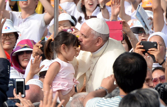 지난 15일 서울 광화문 광장에서 프란치스코 교황의 주례로 열린 한국 초기 순교자 124위 시복식에 앞서 카퍼레이드를 하던 프란치스코 교황이 차를 멈춰 한 어린이의 머리에 입을 맞추고 있다. 서울신문 포토라이브러리