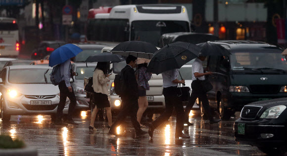 비가 내리는 3일 오전 서울 광화문광장을 지나는 출근길 시민들이 발걸음을 재촉하고 있다.  연합뉴스