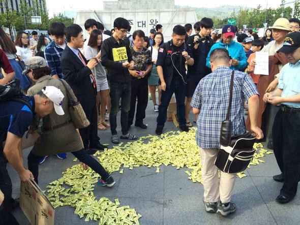 13일 오후 서울 광화문광장 세종대왕상 앞에서 일간베스트·수컷닷컴 회원 30여명이 초코바를 바닥에 흩뿌리는 퍼포먼스를 벌이고 있다. 일간베스트 홈페이지 캡처