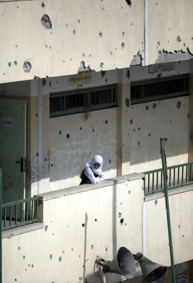 14일(현지시간) 팔레스타인 가자지구 시자이야 지역에서 한 여학생이 개학 첫날 등교한 뒤 학교 건물 난간에 기대어 주변을 살펴보고 있다. 50일간 이어진 이스라엘군의 가자지구 침공을 증언하듯 학교 건물이 누더기처럼 낡아 있다. 시자이야 AP 연합뉴스