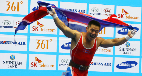 20일 인천 달빛축제정원역도경기장에서 열린 ’2014 인천 아시안게임’ 남자 역도 62k급 A그룹 경기에서 김은국이 용상 3차시기 178kg을 들어올리며 금메달을 확정 지은 뒤 인공기를 펼쳐들고 기뻐하고 있다. 이날 김은국은 인상 154㎏(세계신기록)·용상 178㎏·합계 332㎏(세계신기록)을 기록해 북한에게 두번 째 금메달을 안겼다. 연합뉴스