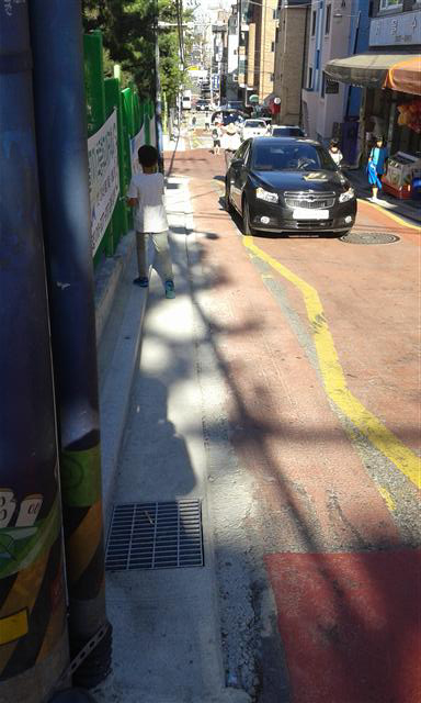지난 18일 강남구 논현2동 학동초등학교 앞에서 한 아이가 앞에 오는 차를 피하기 위해 학교 담장으로 바짝 붙고 있다.