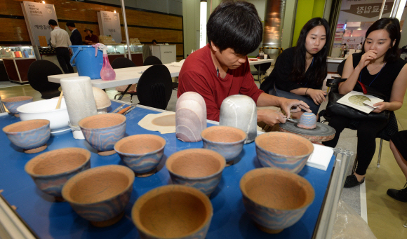 25일 서울 강남구 삼성동 코엑스에서 열린 대한민국공예품대전을 찾은 관람객들이 공예 체험관에서 이천도자기축제추진위원회 관계자가 연리문 찻잔을 만드는 모습을 지켜보고 있다.  손형준 기자 boltagoo@seoul.co.kr