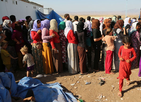 8월12일(현지시간) 시리아로 피난 온 야지디족 사람들이 난민 캠프에서 구호물자를 공급받기 위해 줄 서 있다.  AP/뉴시스