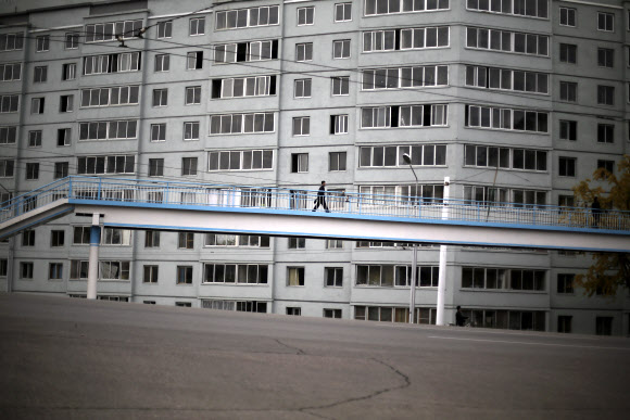 10월 23일 평양의 아파트 사이에 놓인 육교를 지나는 한 북한 남성이 난쟁이처럼 보인다. ⓒAP/뉴시스