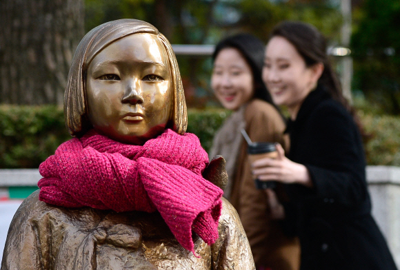 12일 서울 종로구 율곡로2길 일본대사관 앞에서 시민들이 목도리와 장갑을 한 소녀상을 바라보고 있다.  박지환 기자 popocar@seoul.co.kr