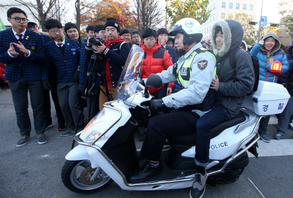 대학수학능력시험일인 13일 오전 한 수험생이 경찰 오토바이를 타고 서울 대치동 휘문고등학교에 마련된 시험장에 도착하고 있다.  연합뉴스