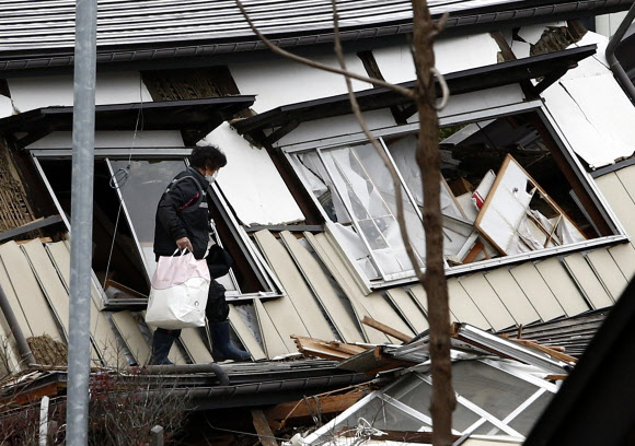지난 22일 일본 나가노현 북부 지역에서 규모 6.8의 강진이 발생했다. 나가노현 하쿠바무라의 한 주민이 23일 무너진 주택에서 옷가지 등을 챙겨 나오고 있다. 일본 기상청은 1주일 내에 여진이 발생할 가능성이 크다고 내다봤다.  나가노 AFP 연합뉴스
