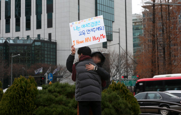 세계 에이즈의 날(12월1일)을 하루 앞둔 30일 오후 서울 보신각 앞에서 한 시민이 ‘나는 에이즈 감염인, 꼭 안아주세요’라고 적힌 팻말을 든 채 프리허그를 하고 있다.  연합뉴스