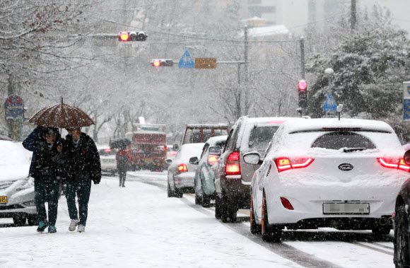 8일 부산에 2㎝ 안팎의 눈이 내리면서 도로 곳곳이 마비된 가운데 부산 사상구의 한 아파트 인근 내리막길에서 차량들이 거북이 걸음으로 운행하고 있다.   연합뉴스