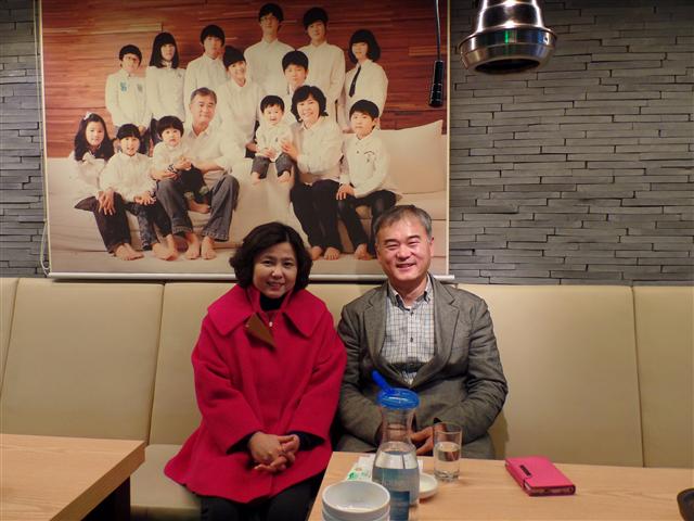 남상돈·이영미씨 부부가 자신들이 운영하는 음식점에서 막내아들 돌 때 찍은 가족사진을 배경으로 환하게 웃고 있다.