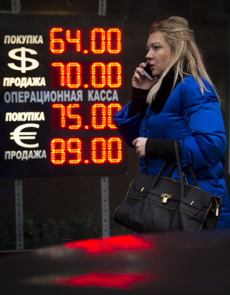 러시아 중앙은행의 기습적인 기준금리 인상에도 16일(현지시간) 러시아 루블화 가치가 사상 처음 달러당 80루블을 돌파한 가운데 한 모스크바 여성이 환전소 전광판 앞을 지나가고 있다. 모스크바 AP 연합뉴스