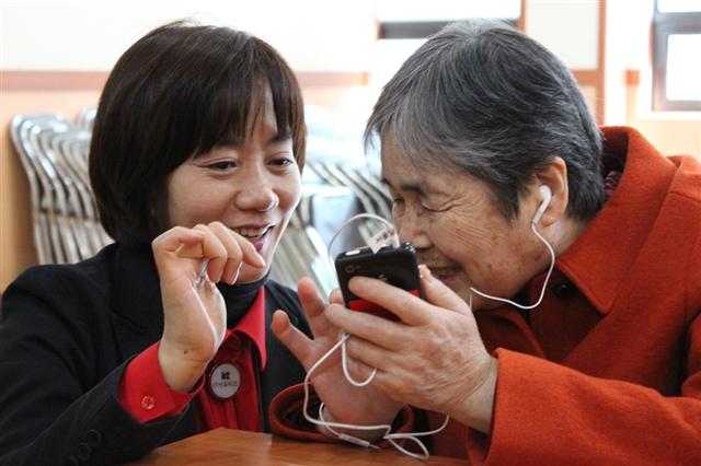 한 여성 IT 서포터스가 시각장애인에게 음성만으로 스마트폰을 사용하는 법을 가르치고 있다. KT 제공