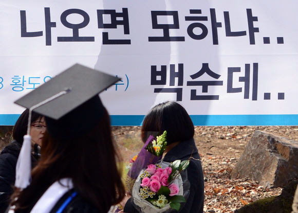 23일 서울 연세대학교에서 열린 졸업식에서 한 학생이 취업에 대해 자조적인 글이 적힌 현수막 앞을 지나고 있다.  박지환 기자 popocar@seoul.co.kr