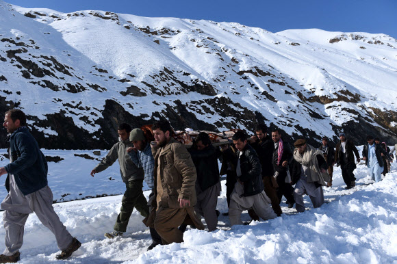 26일(현지시간) 폭설로 인한 눈사태가 일어난 아프가니스탄 수도 카불 북쪽 판지시르 주에서 아프간 남성들이 눈사태로 사망한 희생자들의 시신을 나르고 있다. ⓒAFPBBNews=News1