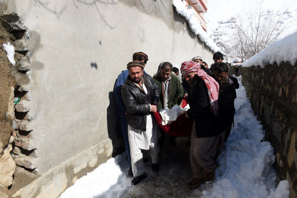 26일(현지시간) 폭설로 인한 눈사태가 일어난 아프가니스탄 수도 카불 북쪽 판지시르 주에서 아프간 남성들이 눈사태로 사망한 희생자들의 시신을 나르고 있다. ⓒAFPBBNews=News1