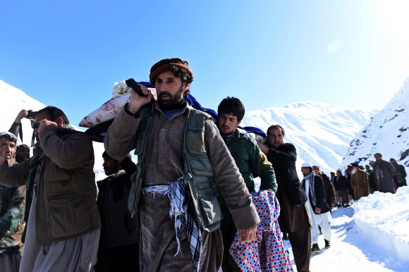 26일(현지시간) 폭설로 인한 눈사태가 일어난 아프가니스탄 수도 카불 북쪽 판지시르 주에서 아프간 남성들이 눈사태로 사망한 희생자들의 시신을 나르고 있다. ⓒAFPBBNews=News1