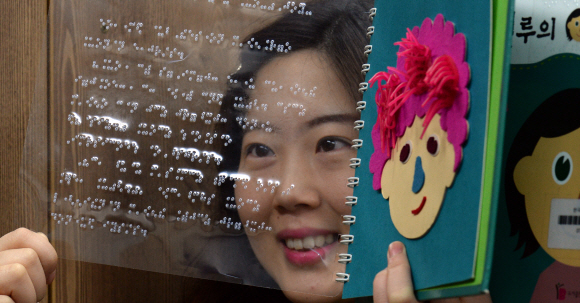 한국점자도서관에서 직원이 시각장애인을 위해 제작한 점자도서와 촉각도서를 들어 보이고 있다.
