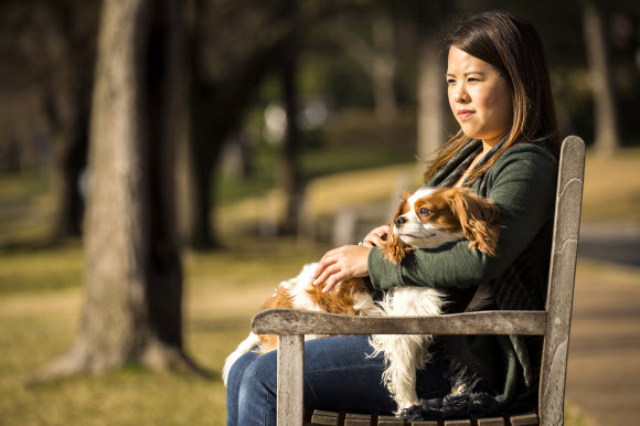 지난해 에볼라 바이러스에 감염됐다가 생존한 니나 팸(26) 텍사스건강장로병원 간호사가 병원 모회사인 ‘텍사스헬스리소시스’를 상대로 소송을 제기할 계획이라고 1일(현지시간) 밝혔다. 사진은 지난 2월25일 팸이 댈러스의 한 공원에서 강아지와 함께 휴식을 취하고 있는 모습.  AP/뉴시스
