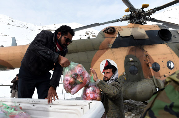 1일(현지시간) 눈사태로 많은 희생자가 발생한 아프가니스탄 북서부 판지시르 주의 한 마을에서 아프간 군인들이 군 헬기로 운송해 온 구호물품들을 눈사태 생존자들에게 나눠주고 있다. ⓒAFPBBNews=News1