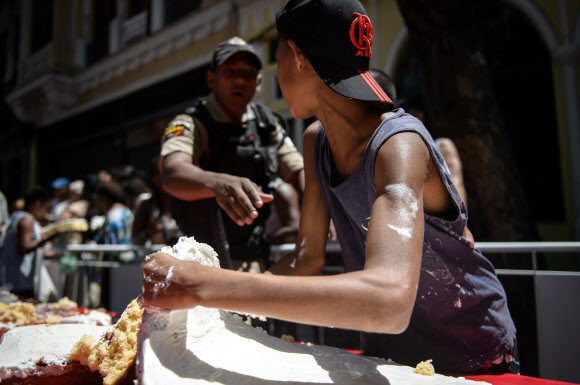 1일(현지시간) 브라질 리우데자네이루시 설립 450주년 기념축제가 열린 가운데 450m 길이의 U자 모양 케익을 먹기 위해 사람들이 줄을 서서 기다리고 있다. 사진은 한 소년이 케익 일부를 뜯어가는 모습. ⓒAFPBBNews=News1