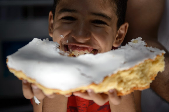 1일(현지시간) 브라질 리우데자네이루시 설립 450주년 기념축제가 열린 가운데 한 소년이 450m 길이의 U자 모양 케익의 일부를 받고 해맑게 웃고 있다.  ⓒAFPBBNews=News1
