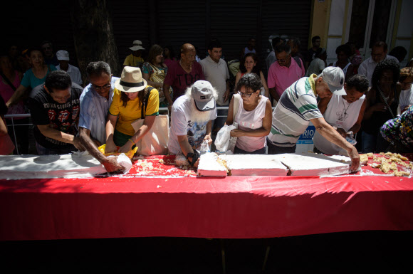 1일(현지시간) 브라질 리우데자네이루시 설립 450주년 기념축제가 열린 가운데 450m 길이의 U자 모양 케익을 먹기 위해 사람들이 줄을 서서 기다리고 있다. 사진은 축제에 온 참가자들이 케익을 잘라 먹고 있는 모습.  ⓒAFPBBNews=News1