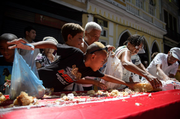 1일(현지시간) 브라질 리우데자네이루시 설립 450주년 기념축제가 열린 가운데 450m 길이의 U자 모양 케이크를 먹기 위해 사람들이 줄을 서서 기다리고 있다. 사진은 축제에 온 참가자들이 케이크를 잘라 먹고 있는 모습.  ⓒAFPBBNews=News1