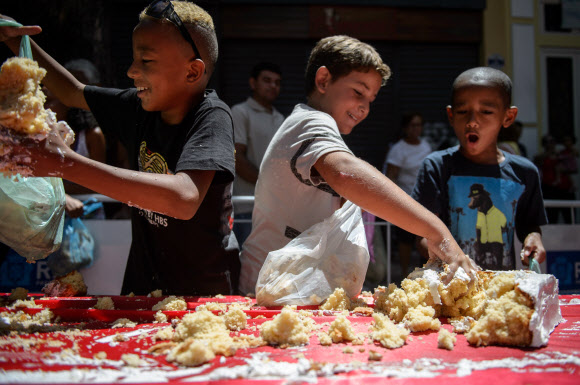 1일(현지시간) 브라질 리우데자네이루시 설립 450주년 기념축제가 열린 가운데 450m 길이의 U자 모양 케익을 먹기 위해 사람들이 줄을 서서 기다리고 있다. 사진은 축제에 온 참가자들이 케익을 잘라서 봉투에 담고 있는 모습.  ⓒAFPBBNews=News1