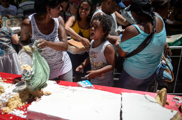 1일(현지시간) 브라질 리우데자네이루시 설립 450주년 기념축제가 열린 가운데 450m 길이의 U자 모양 케익을 먹기 위해 사람들이 줄을 서서 기다리고 있다. 사진은 축제에 온 참가자들이 케익을 잘라 먹고 있는 모습.  ⓒAFPBBNews=News1